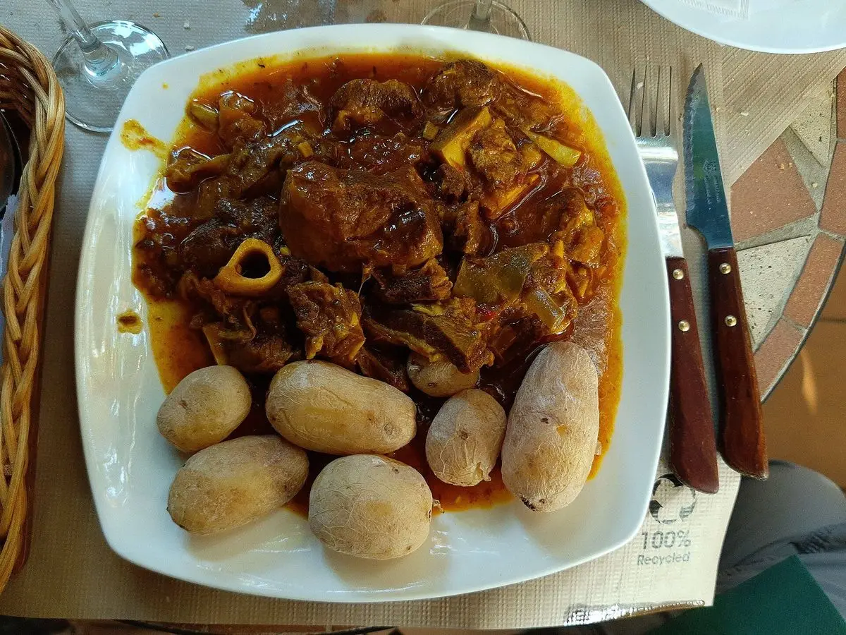 Fuente con carne guisada en salsa oscura y papas arrugadas