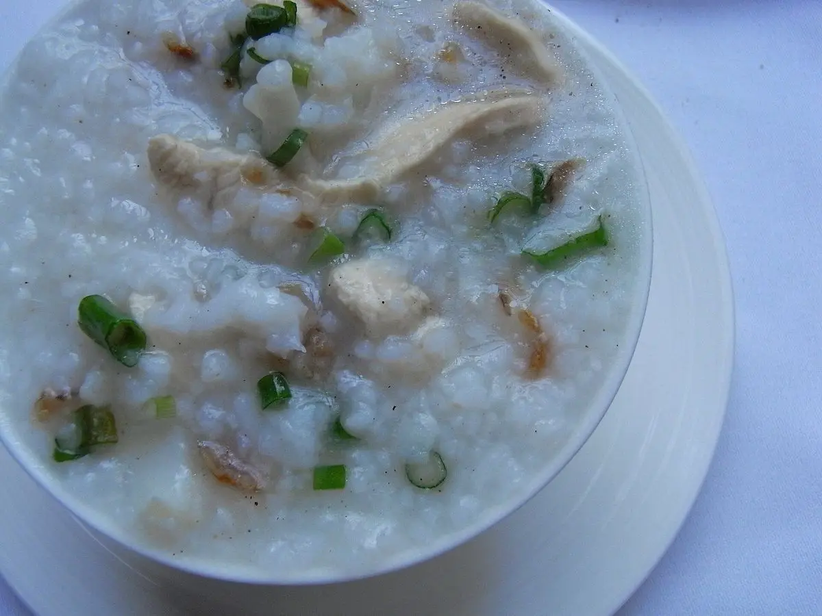 Cuenco de arroz caldoso con tiras de pollo y cebolleta picada