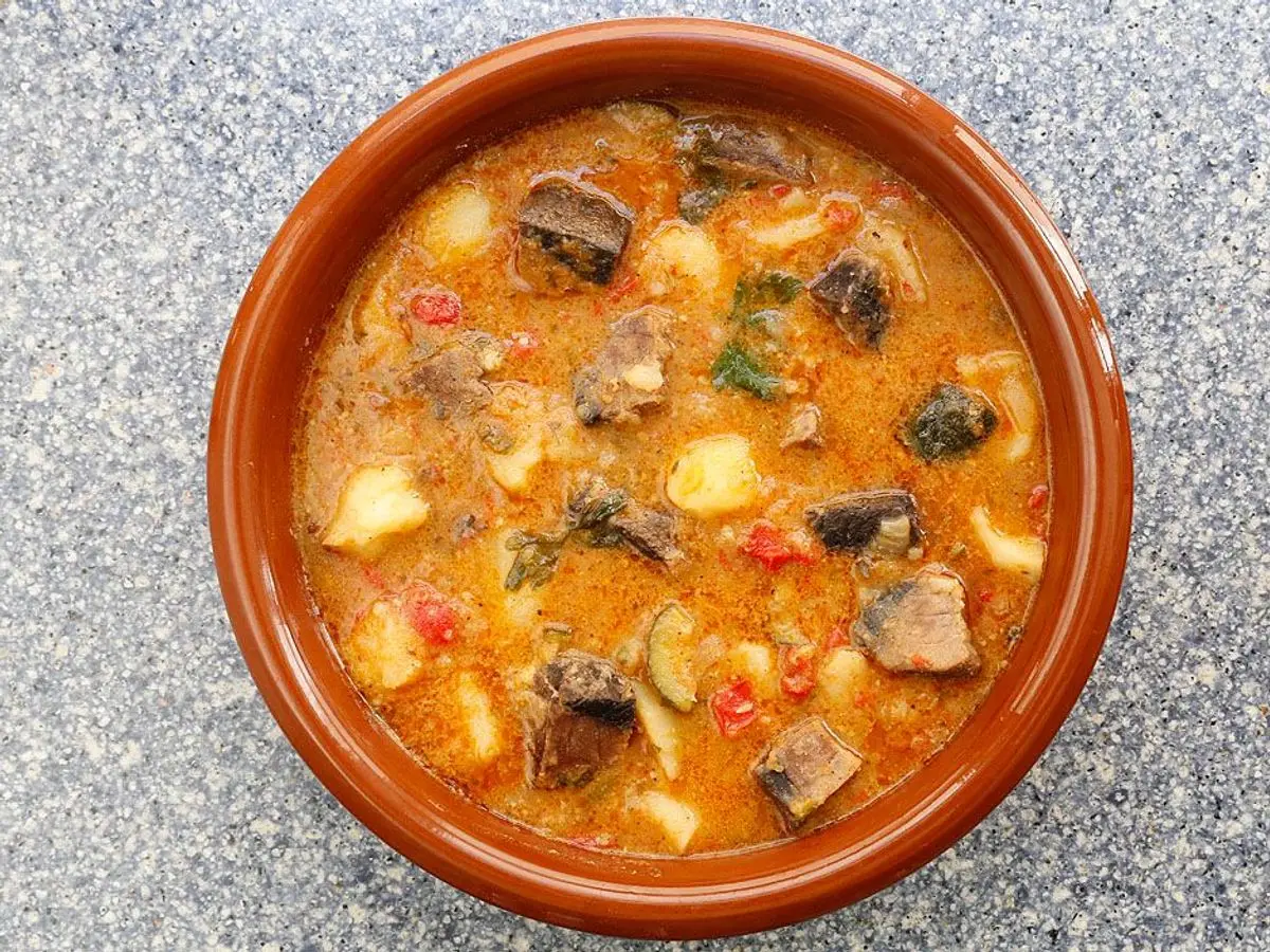 Guiso de pescado con patatas y pimiento en salsa de tomate servido en una cazuela de barro