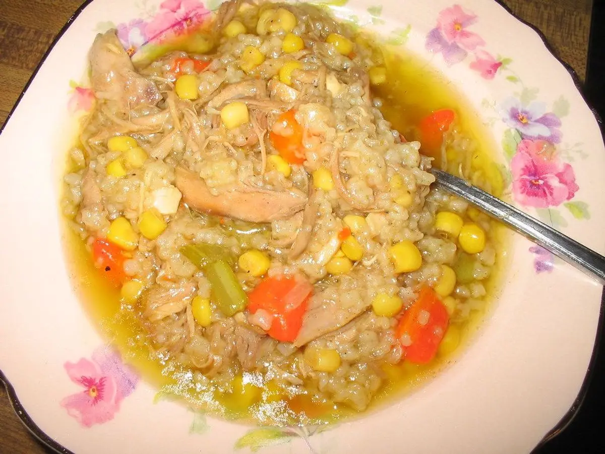 Plato hondo de guiso de carne desmenuzada con zanahoria, maíz y verduras en caldo