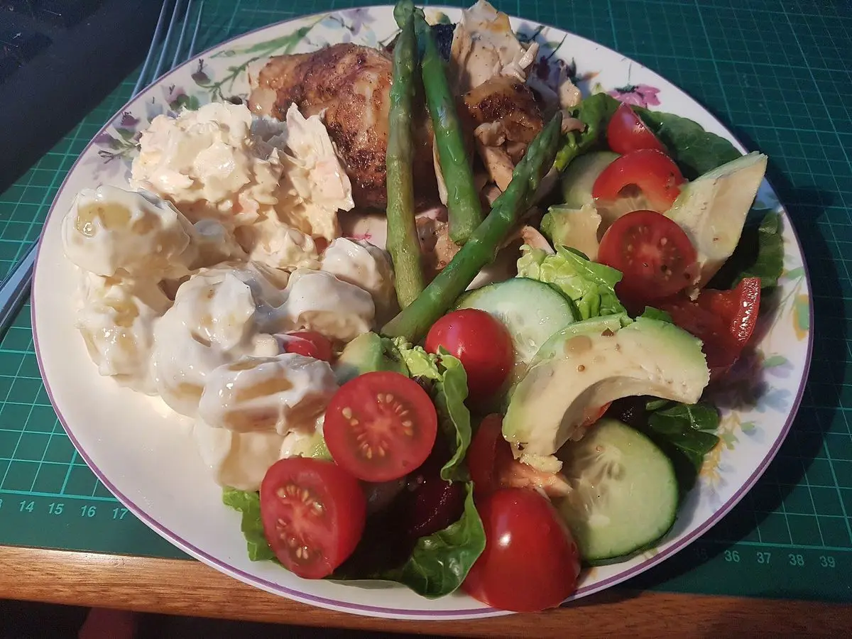 Contramuslos de pollo asados con espárragos, ensalada de patata y col y tomates cherry
