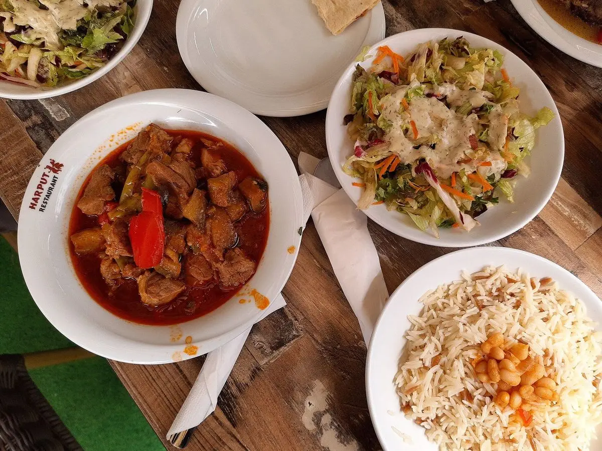 Cuenco de guiso de cordero con berenjena y pimiento rojo, junto a arroz con garbanzos y ensalada