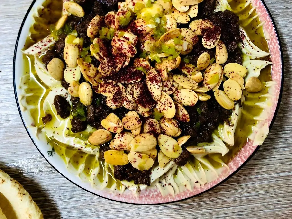 Plato con carne de cordero especiada, garbanzos, frutos secos y pasas sobre pan