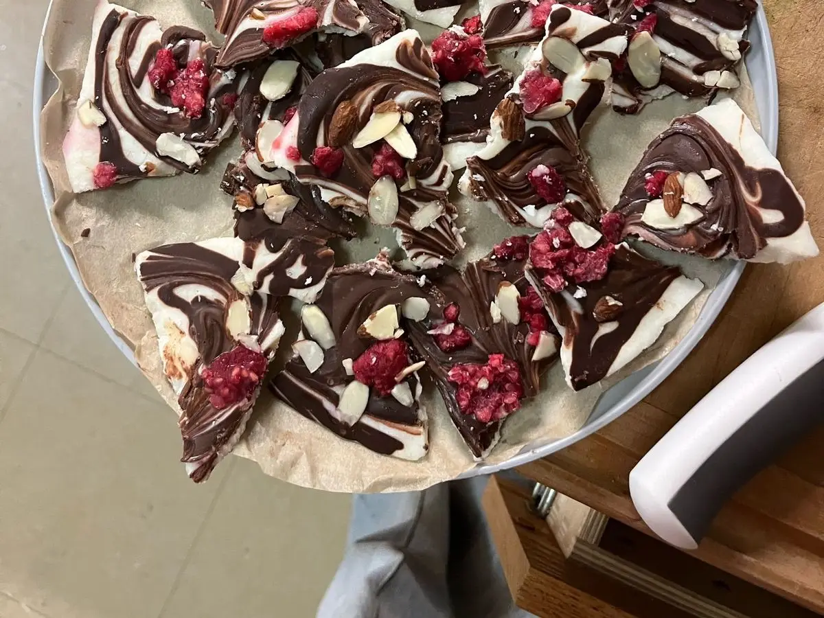 Trozos de corteza helada de yogur y chocolate con frutos rojos sobre una fuente