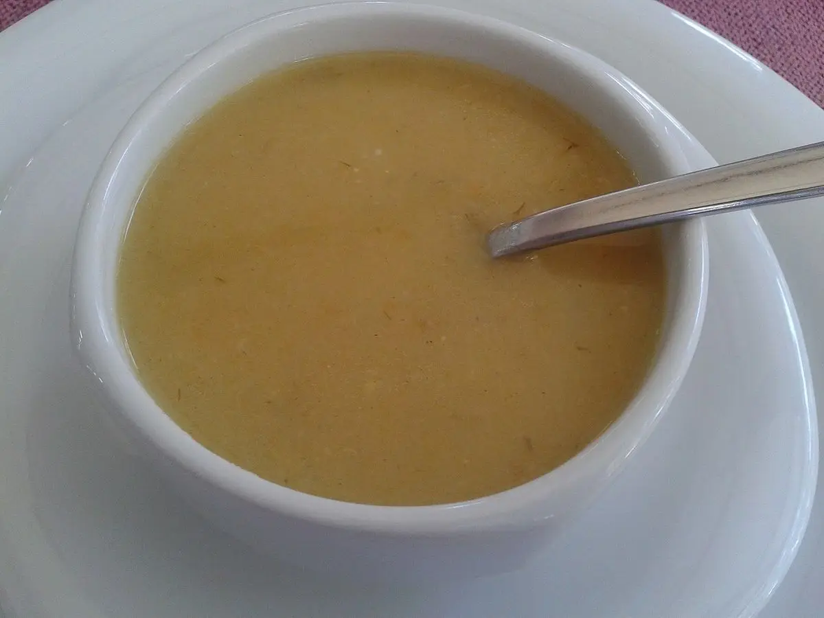 Cuenco blanco de crema suave de color crema con una cuchara sobre un plato blanco