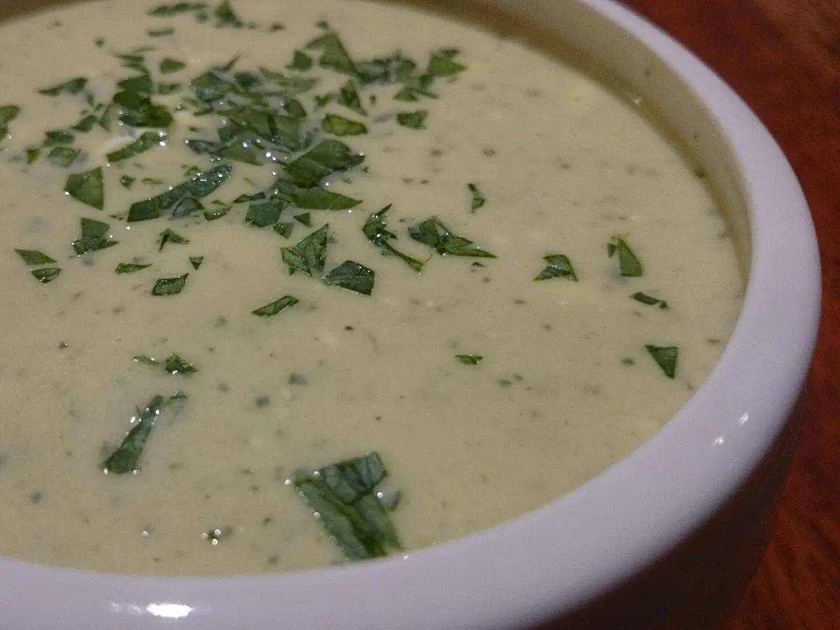 Plato hondo de crema clara de apio con hierbas frescas picadas por encima