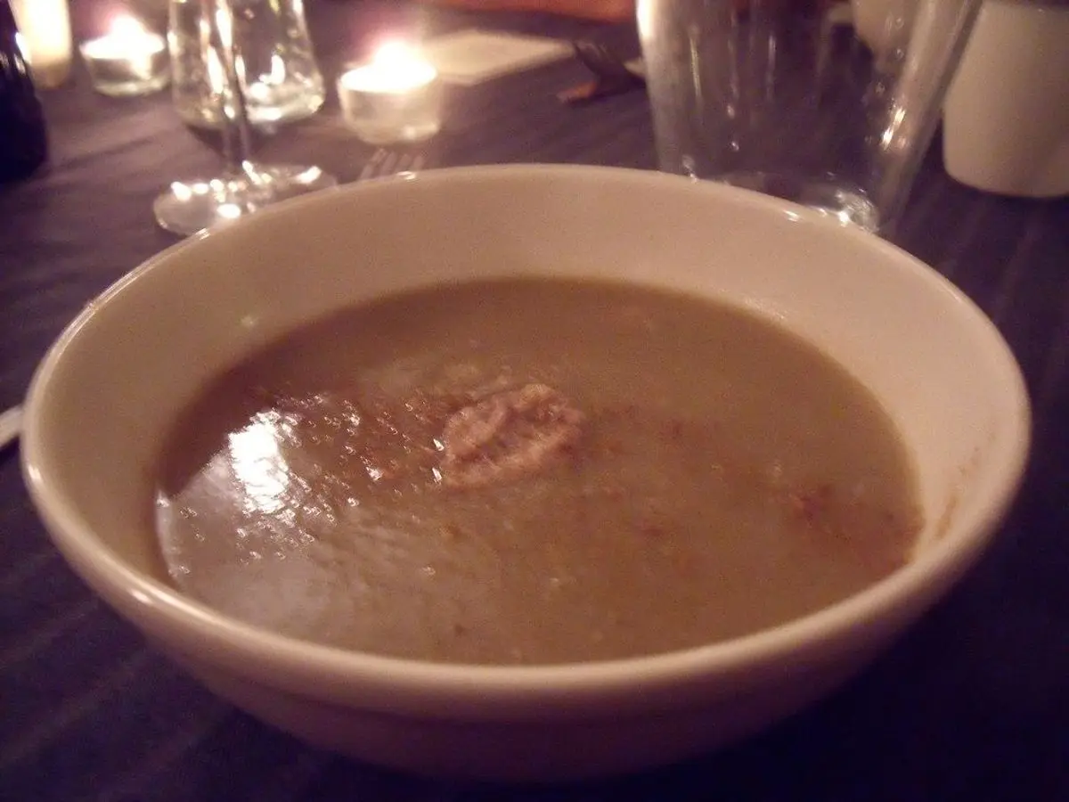Cuenco blanco de crema oscura y espesa de berenjena servida en un plato hondo