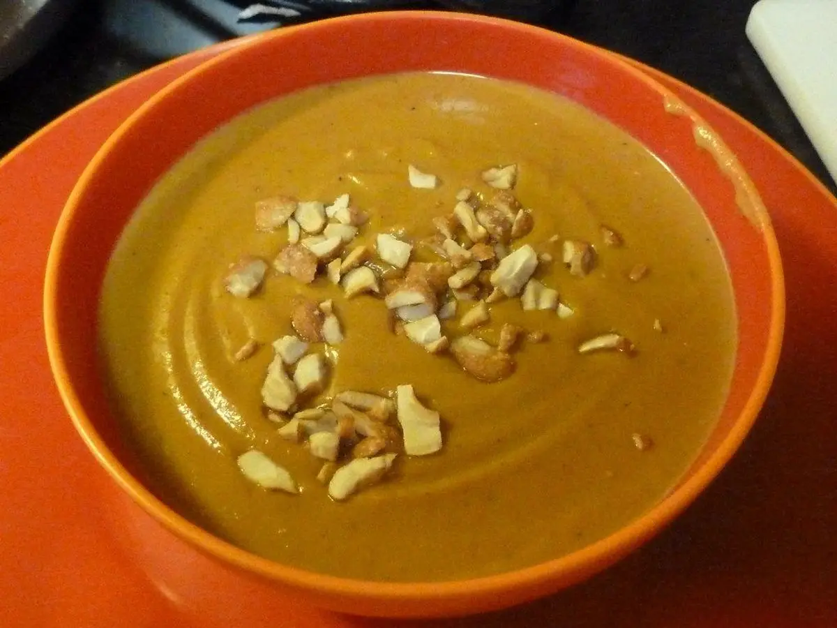 Cuenco naranja de crema espesa de boniato con frutos secos picados por encima