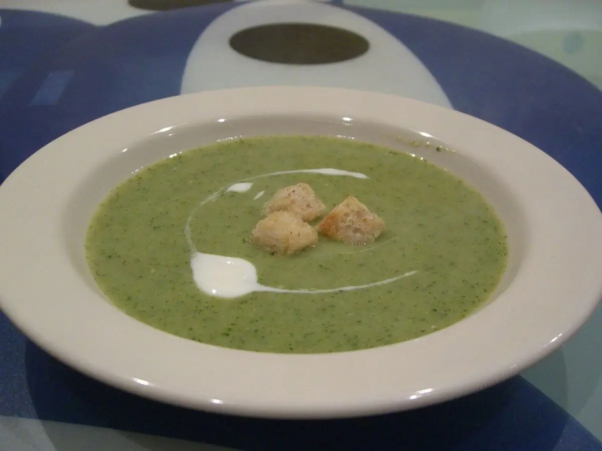 Plato hondo de crema verde de brócoli con picatostes y un hilo de nata
