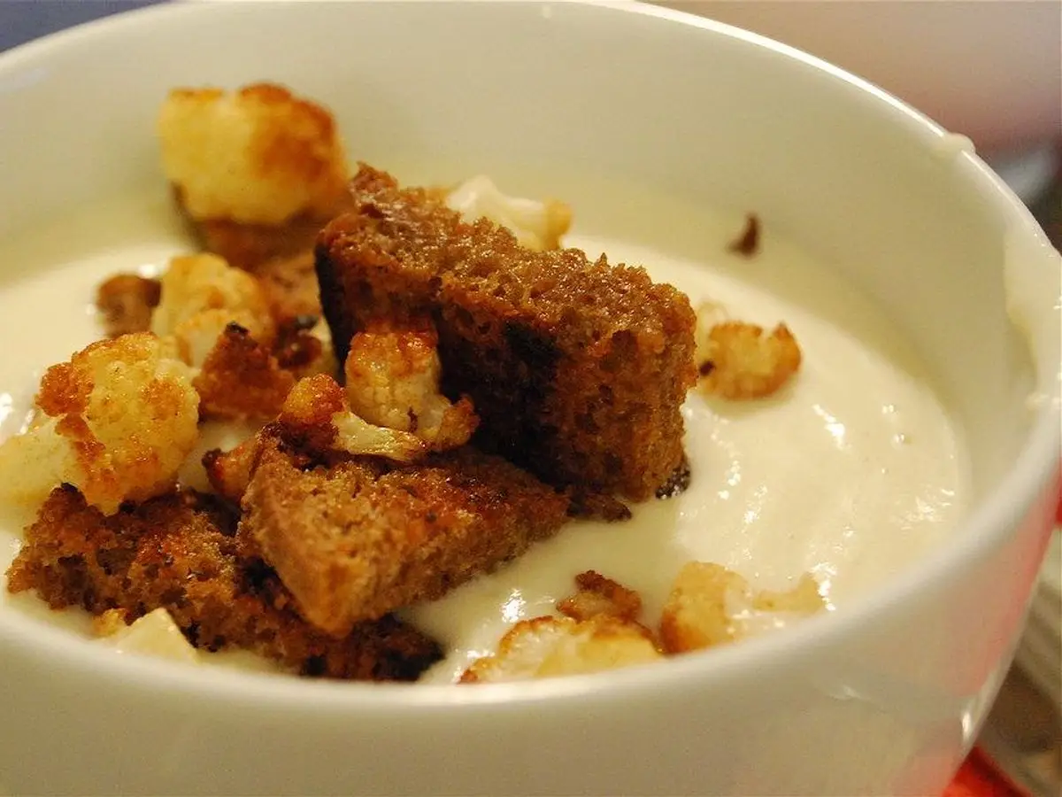 Cuenco blanco de crema de coliflor con daditos de pan tostado por encima