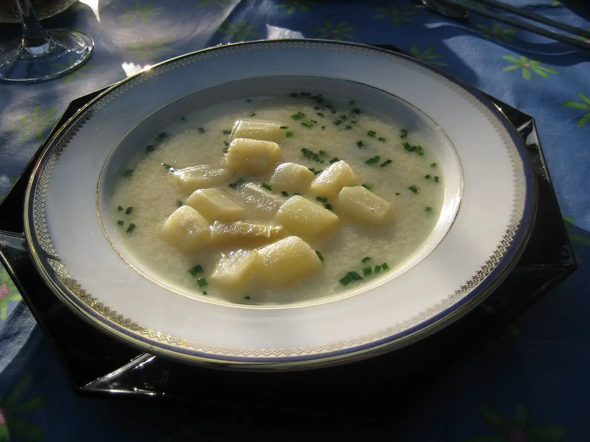 Plato hondo de crema de espárragos blancos con trozos de espárrago y cebollino picado