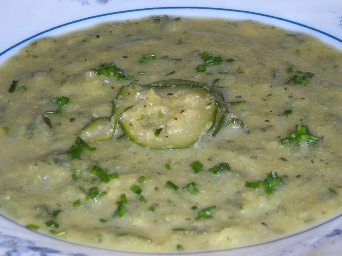Plato de crema verde de calabacín con una rodaja de calabacín y hierbas picadas por encima