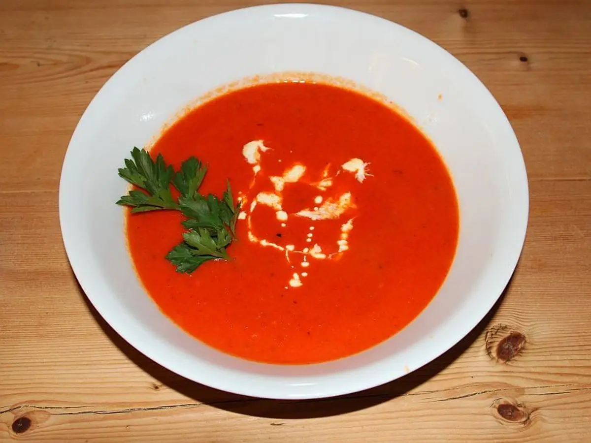 Cuenco blanco de crema de tomate roja con perejil y un toque de queso blanco