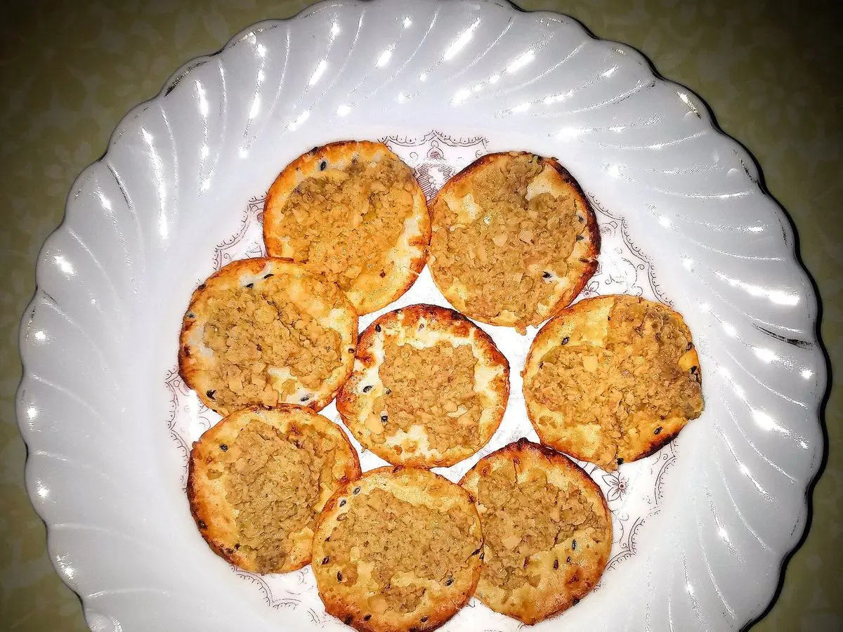 Plato blanco ondulado con crujientes de arroz dorados untados con una crema