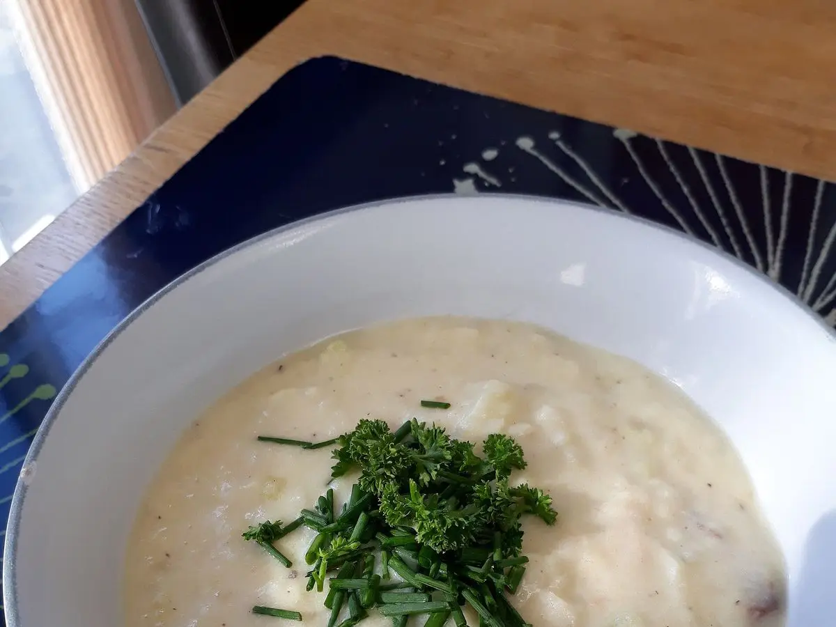 Cuenco blanco de sopa cremosa de pescado ahumado y patata con cebollino picado