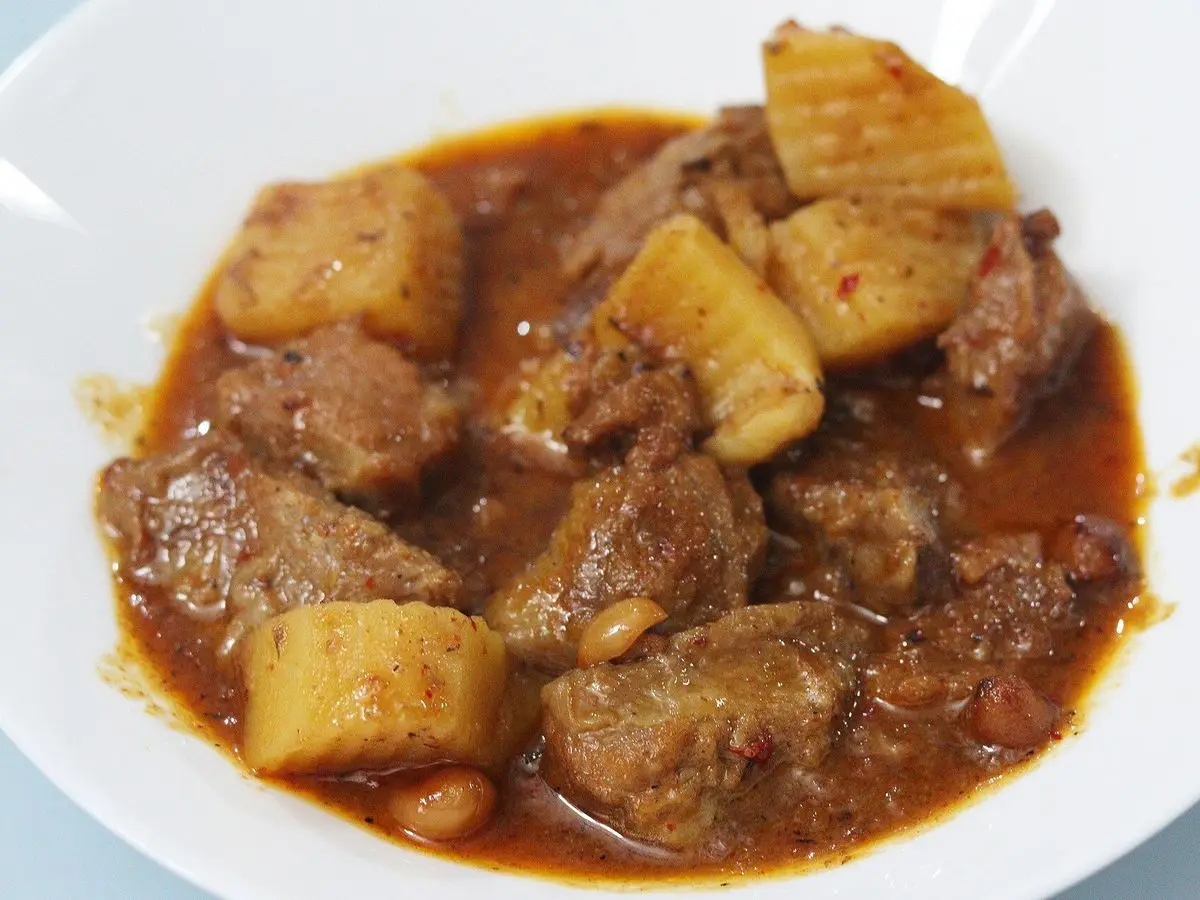 Curry massaman con trozos de ternera y patata en salsa rojiza en un plato hondo blanco