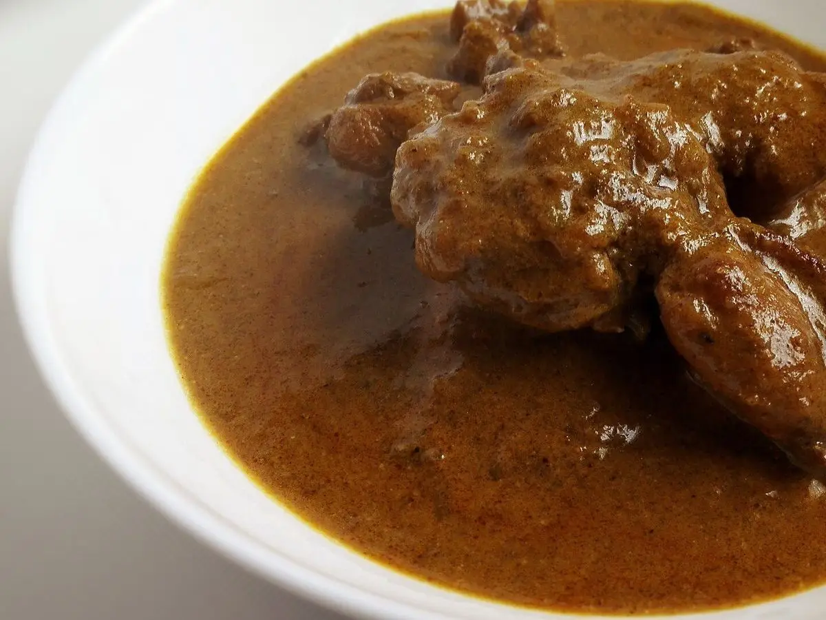 Trozos de carne guisada en una salsa de curry marrón oscura en un plato blanco