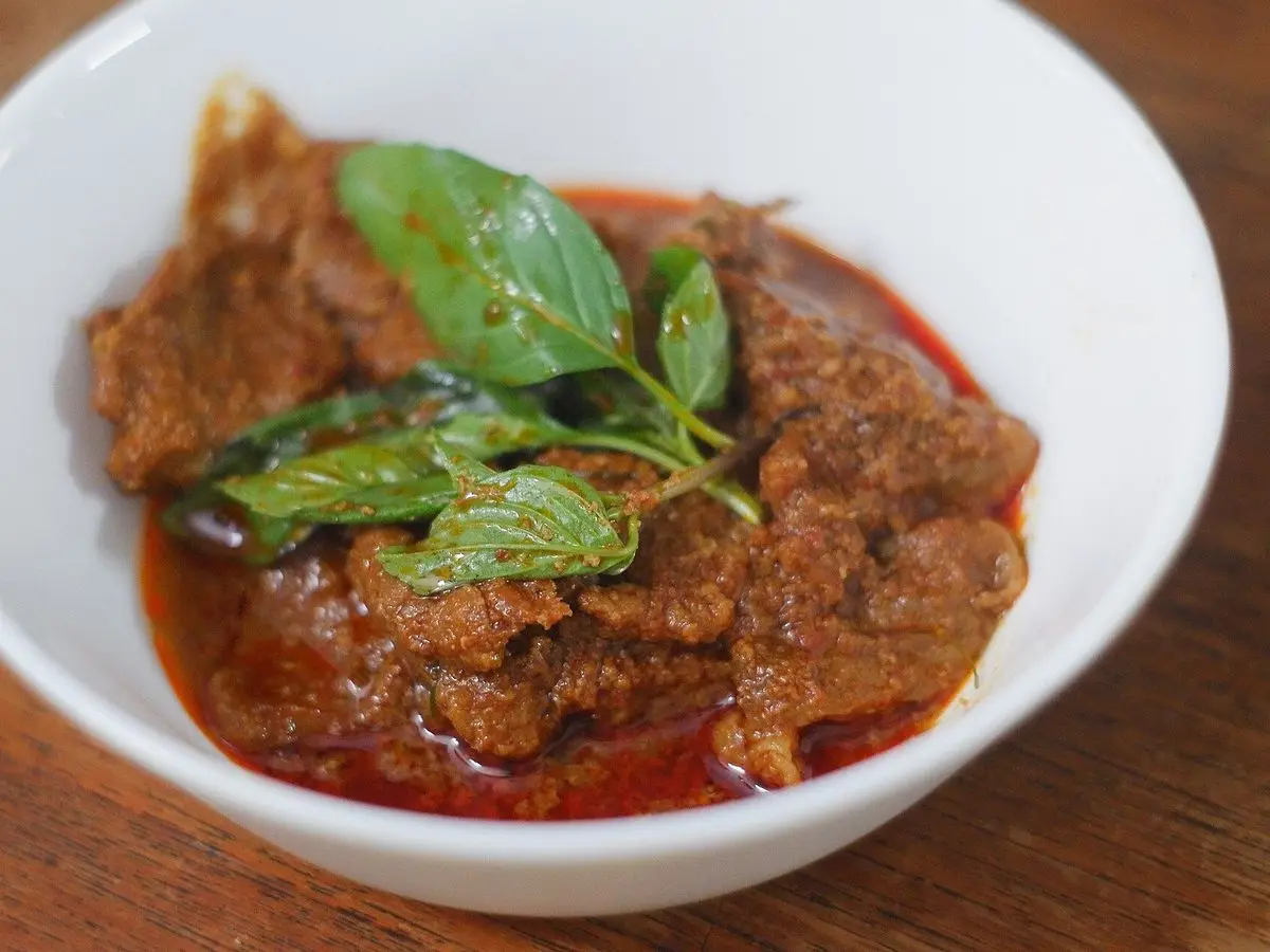 Cuenco blanco de curry rojo de ternera con hojas de albahaca por encima