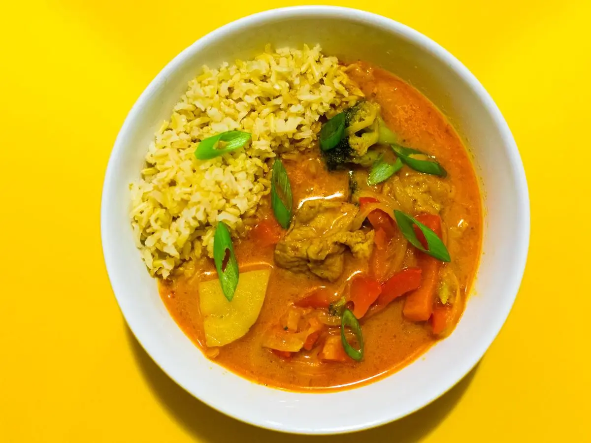 Cuenco amarillo de curry rojo con verduras, judías verdes y arroz