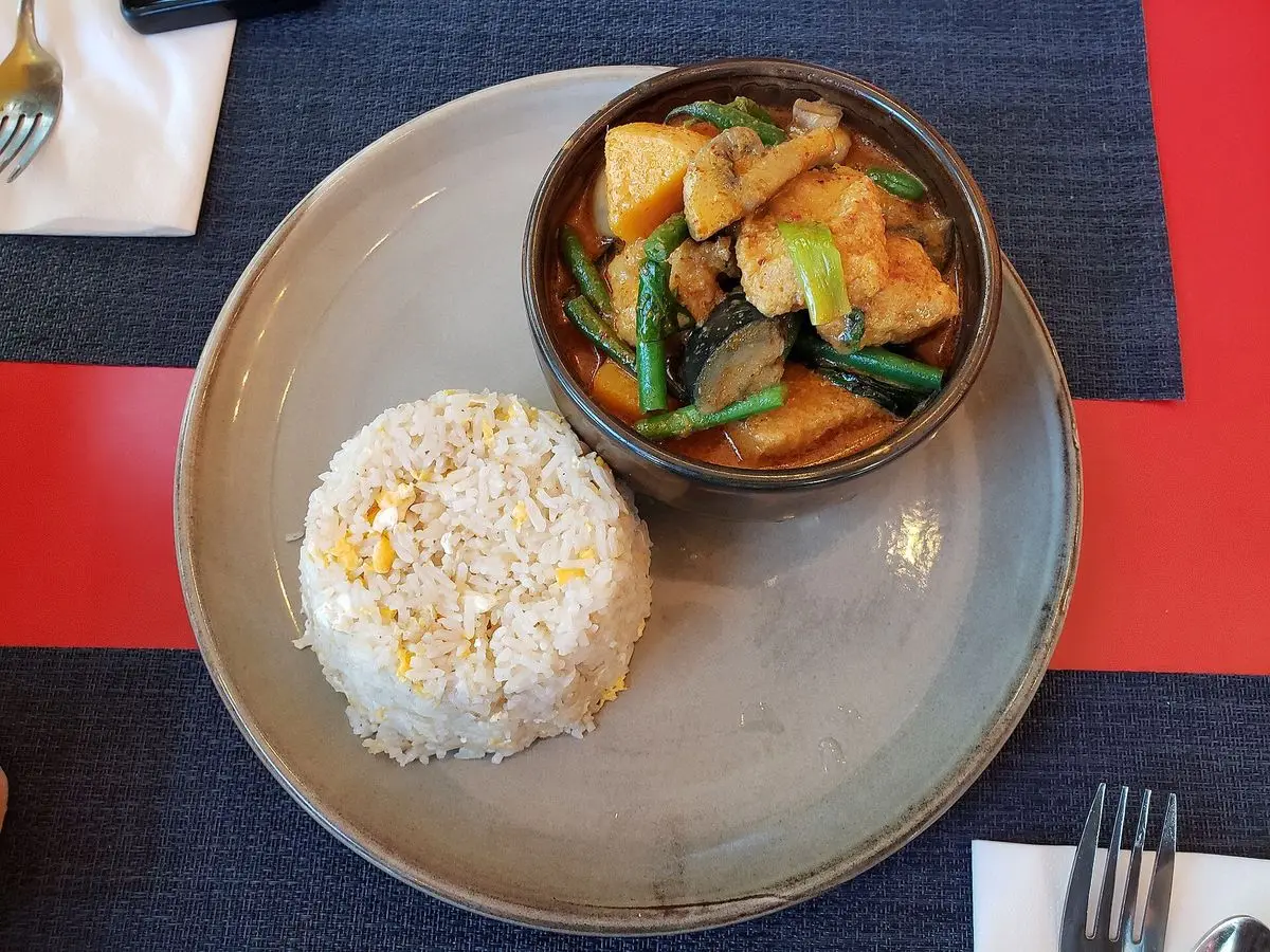 Cuenco de curry de tofu con verduras y judías verdes junto a una porción de arroz blanco