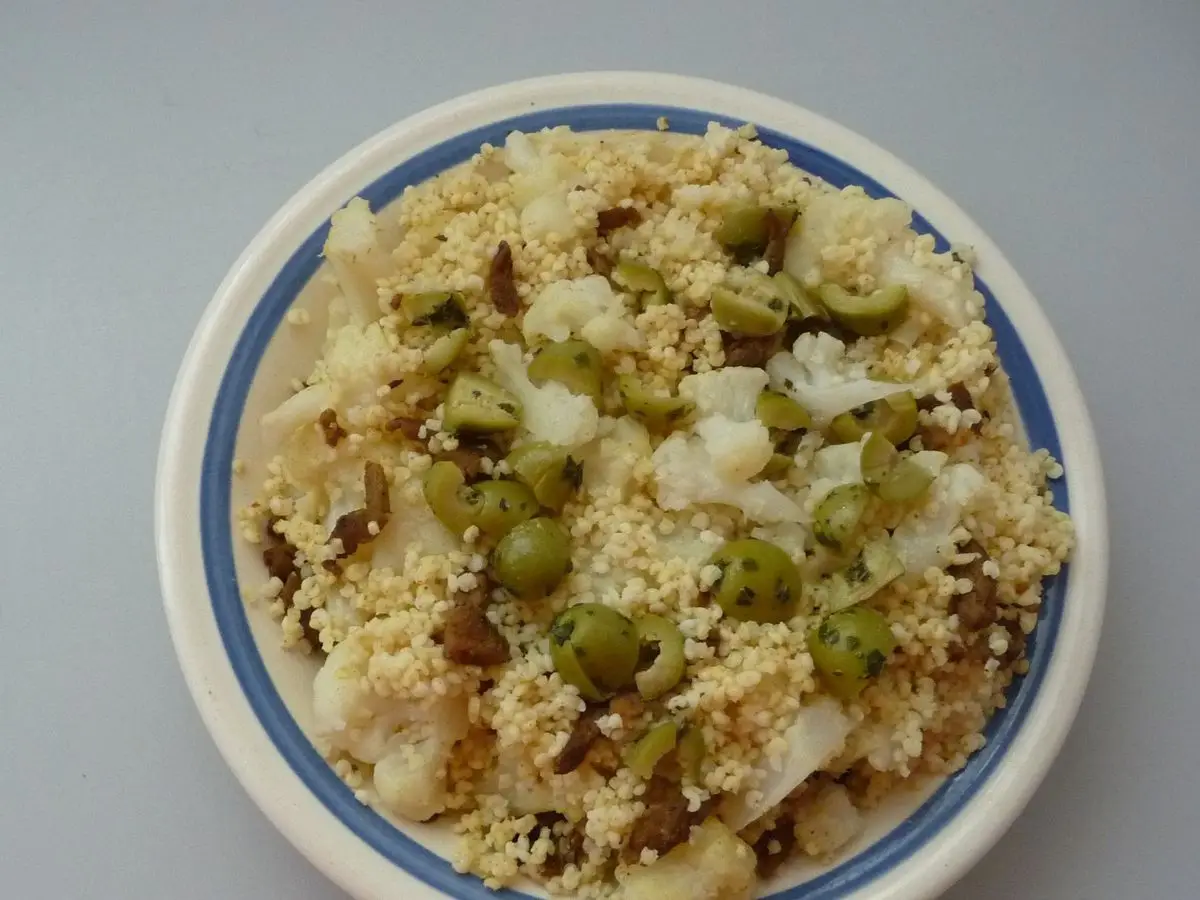 Plato de cuscús con guisantes y trozos de verdura blanca, visto desde arriba