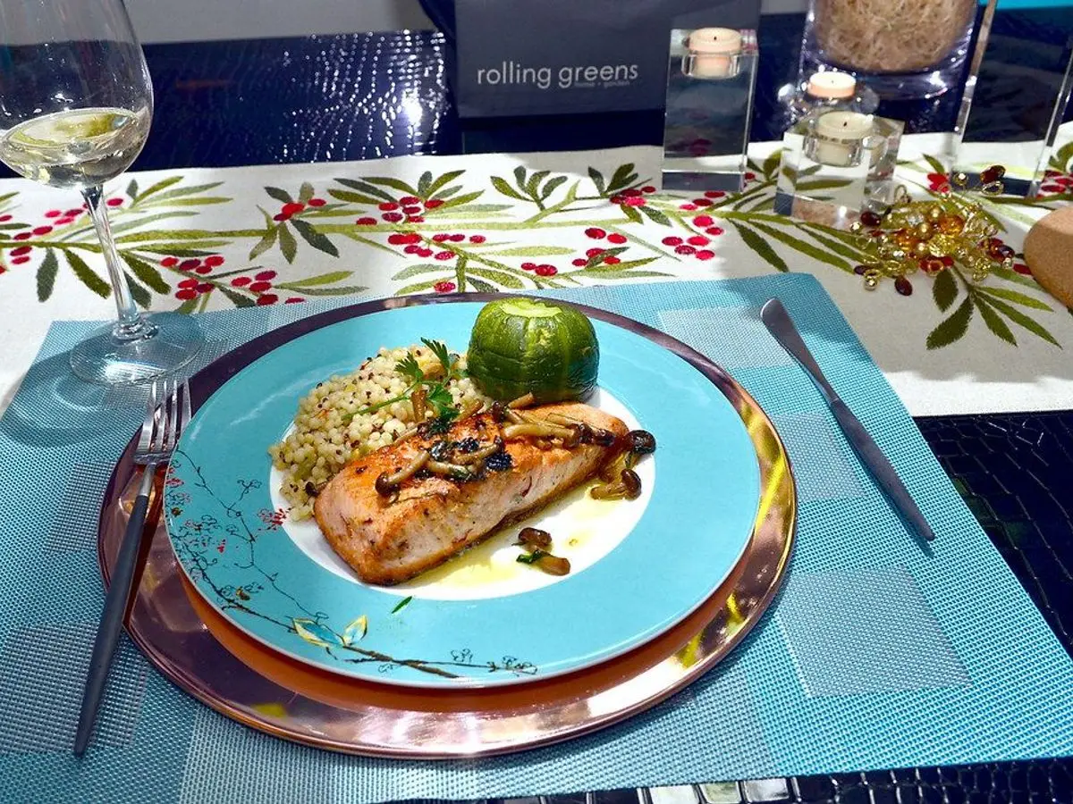 Filete de pescado a la plancha con guarnición de cereal verde y medio limón en un plato azul