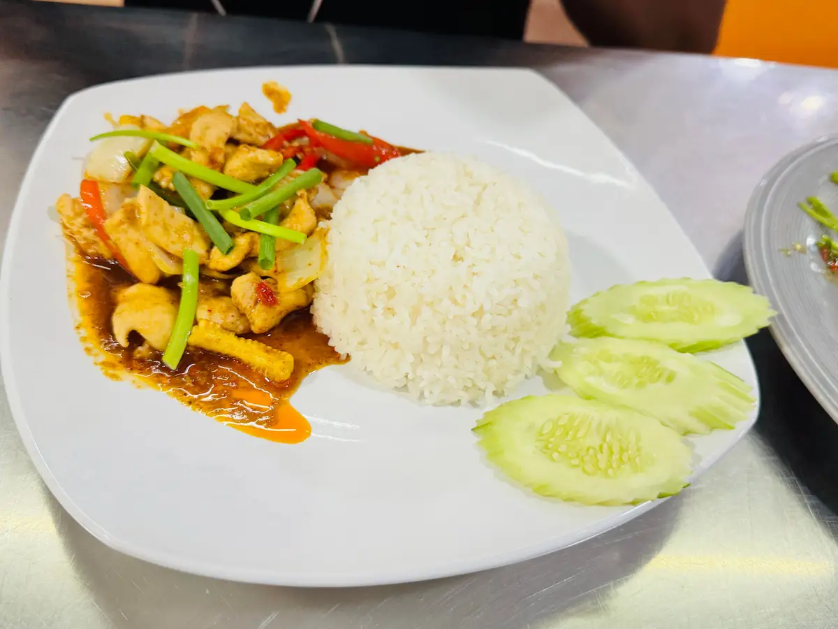 Pollo salteado con verduras junto a una cúpula de arroz y pepino