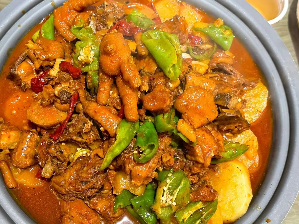 Cazuela de pollo guisado con patata, pimiento verde y guindilla en salsa roja