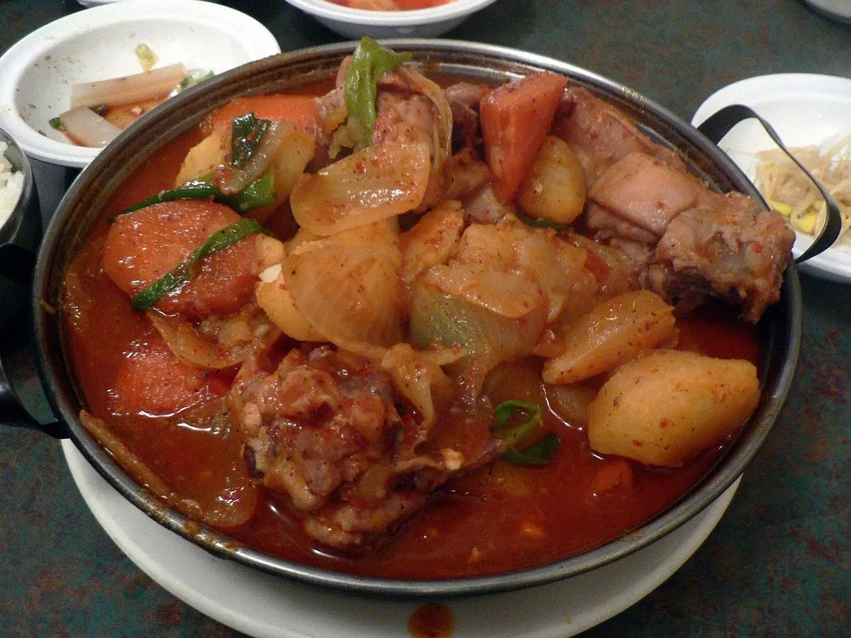 Cazuela de guiso picante de pollo con patata, zanahoria y cebolla en salsa roja