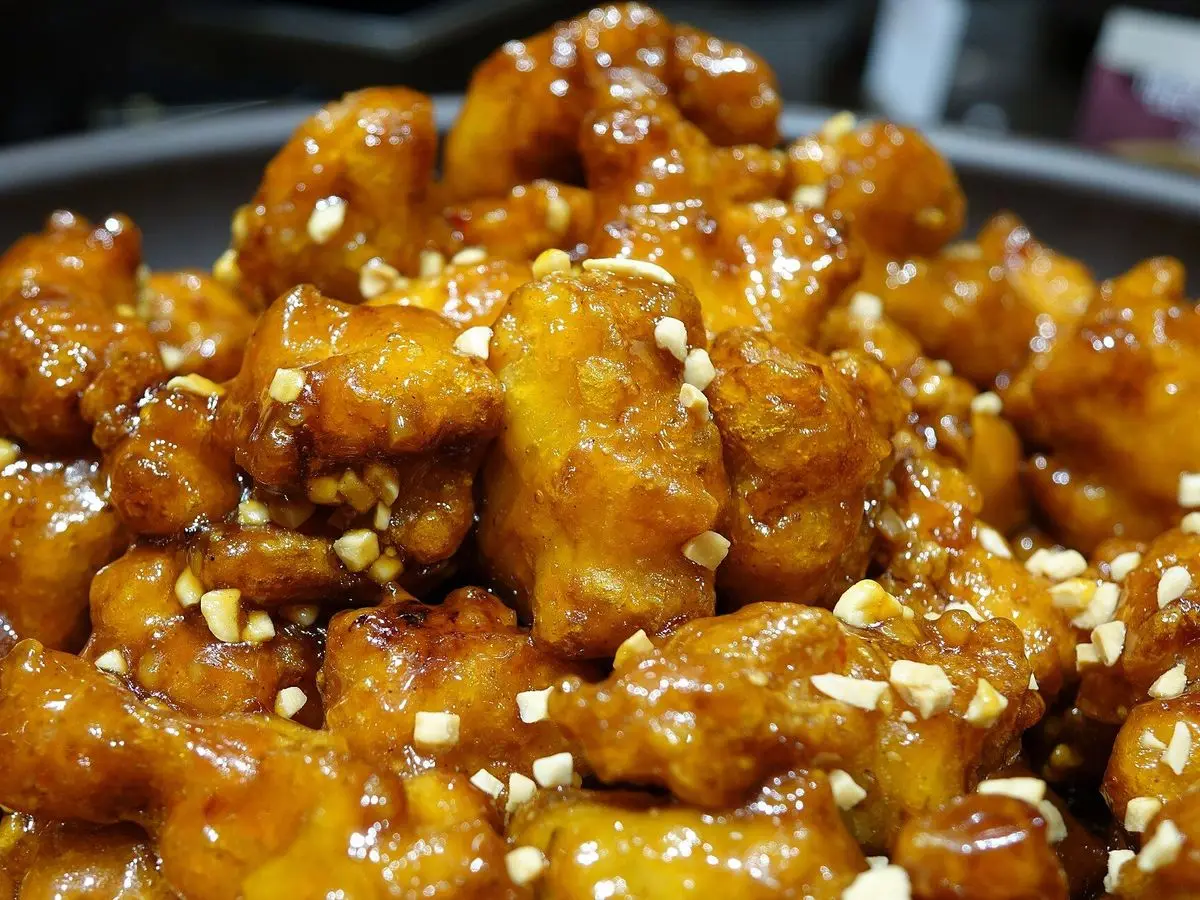 Trozos de pollo frito coreano crujiente glaseado en salsa dulce con semillas de sésamo