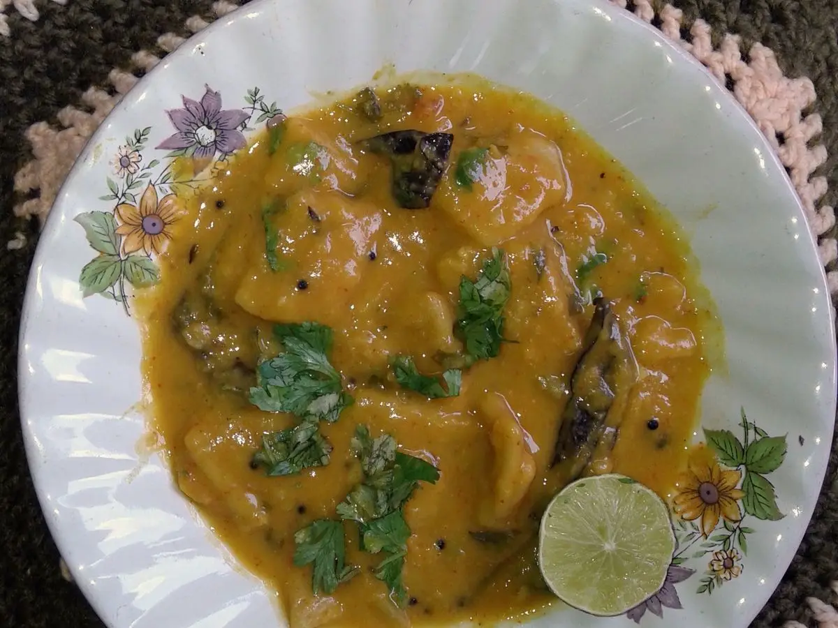 Plato de dal dhokli con salsa amarilla, cilantro y rodaja de lima