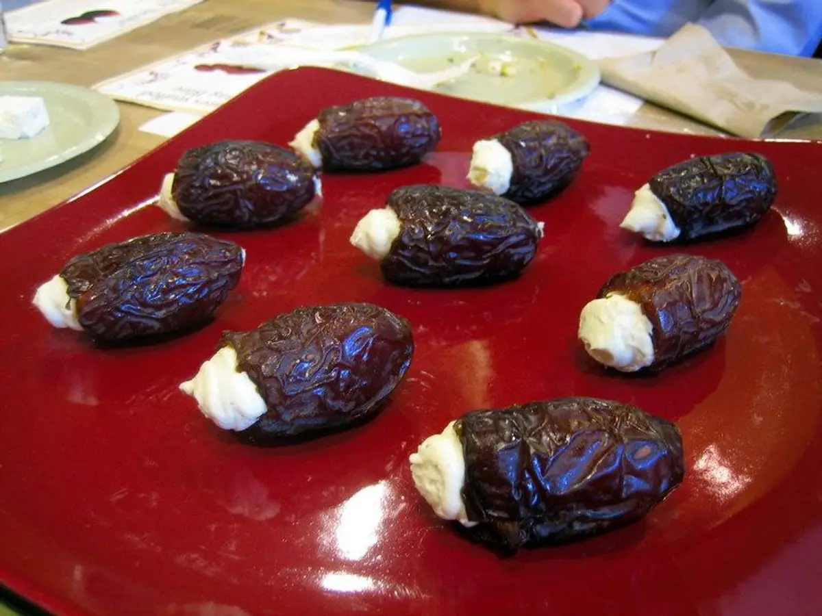 Dátiles abiertos y rellenos de queso fresco blanco dispuestos sobre una bandeja roja
