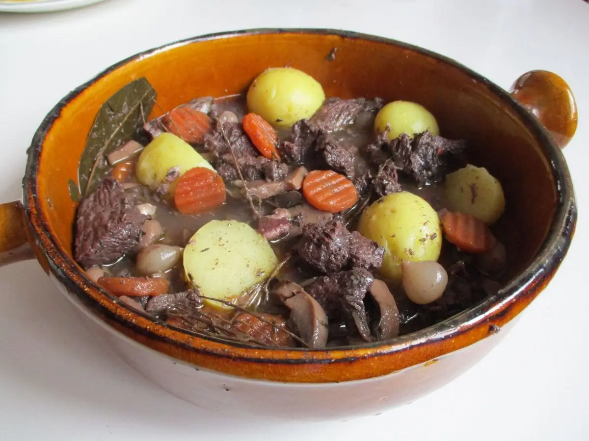 Cazuela de barro con guiso de ternera con zanahoria, patatas y laurel