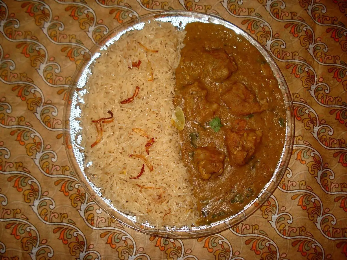 Plato con arroz especiado con azafrán a un lado y guiso de carne y lentejas en salsa marrón al otro