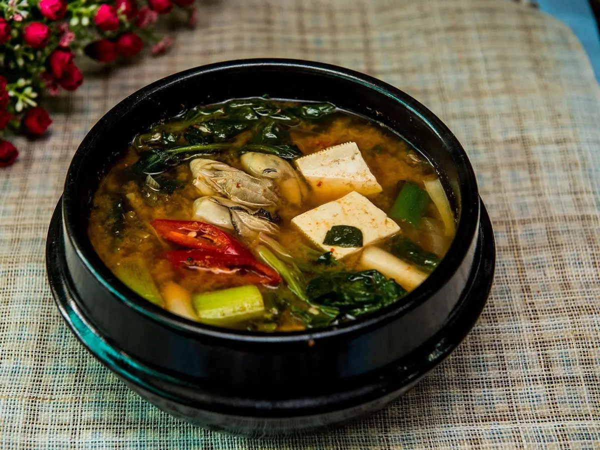 Cazuela negra de guiso coreano de pasta de soja con tofu, calabacín y guindilla roja