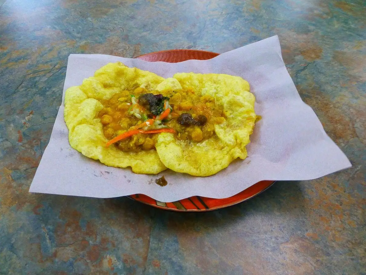 Doubles de Trinidad, pan bara amarillo relleno de garbanzos al curry sobre papel en un plato