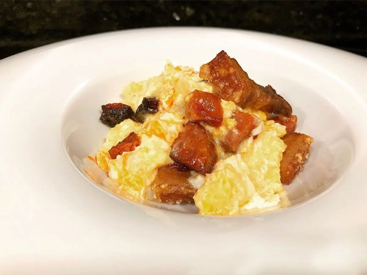 Plato con huevos revueltos y trozos de panceta frita