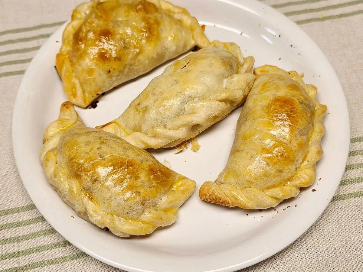 Empanadas doradas al horno con repulgue servidas en un plato blanco