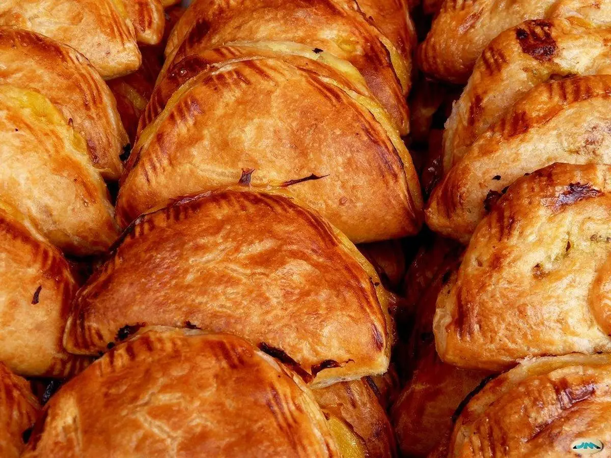 Empanadillas doradas de hojaldre amontonadas en una bandeja