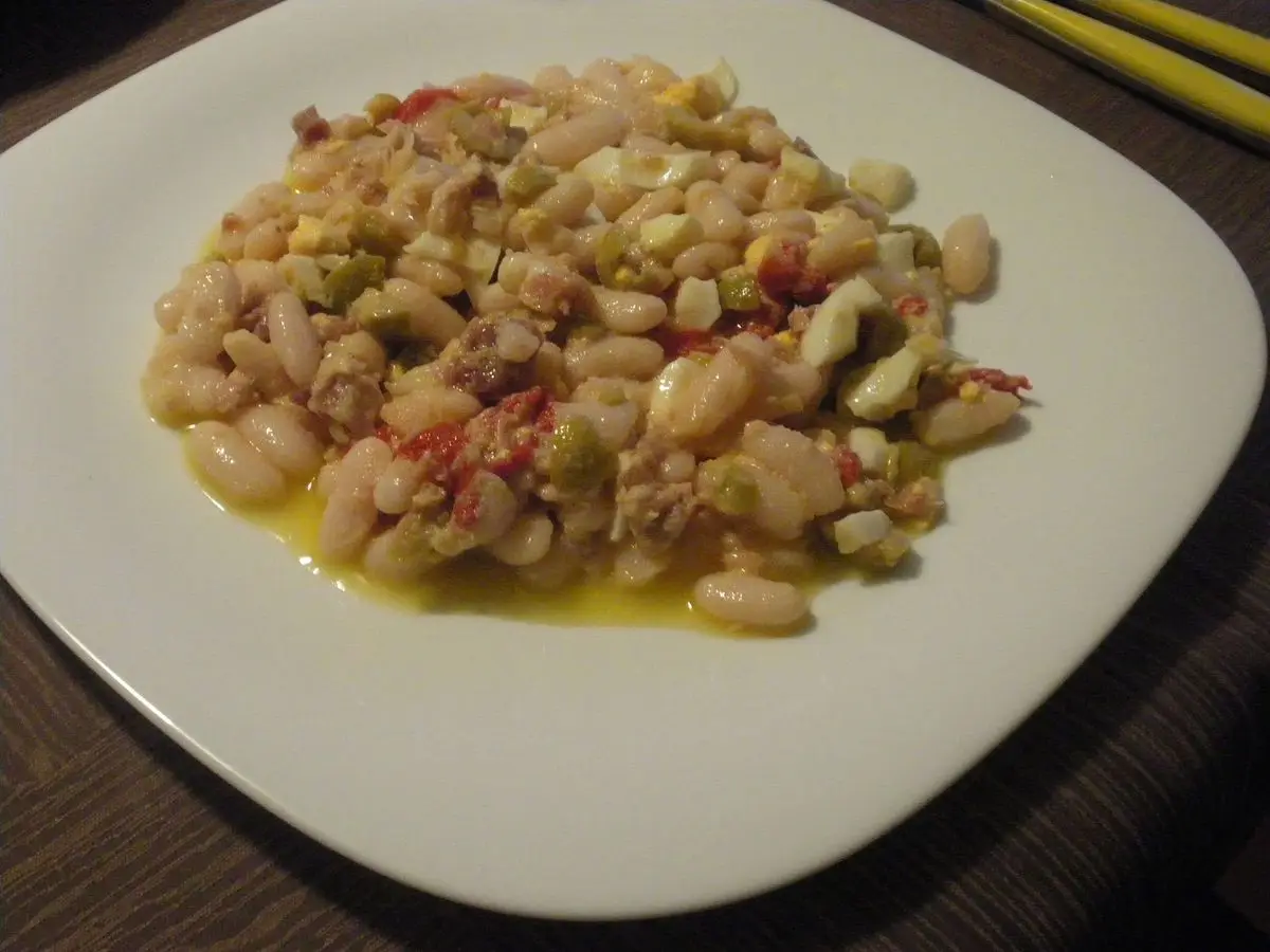 Ensalada de alubias blancas con tomate y aliño de aceite en un plato cuadrado blanco