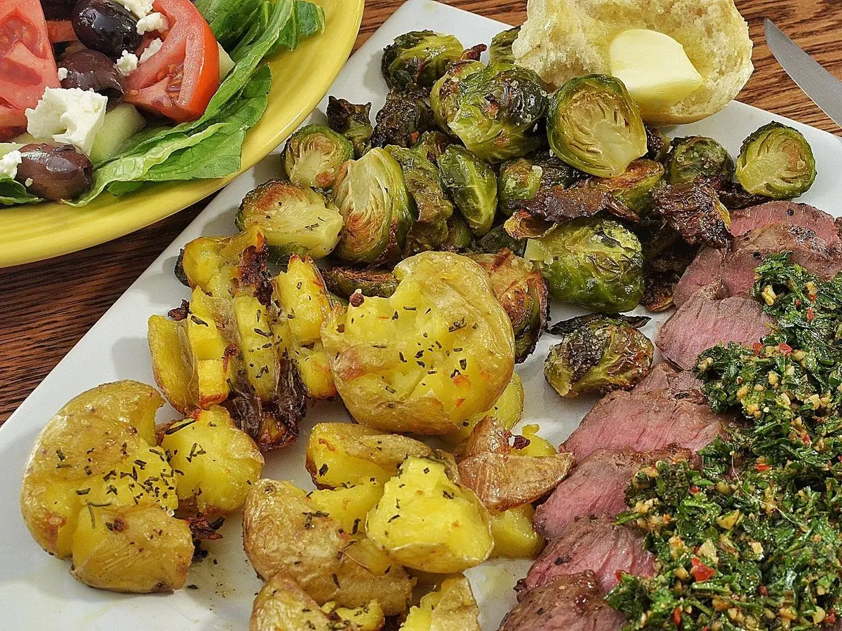 Plato con filetes de ternera con chimichurri, patatas chafadas y coles de Bruselas asadas