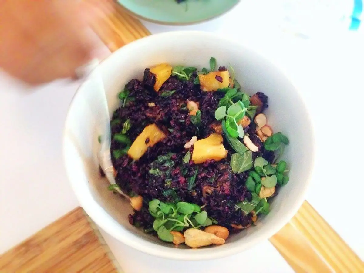 Cuenco blanco de ensalada de arroz negro con hierbas y trocitos dorados