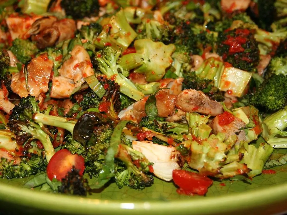 Plato verde de ensalada de brócoli asado con trozos de pollo y pimiento rojo