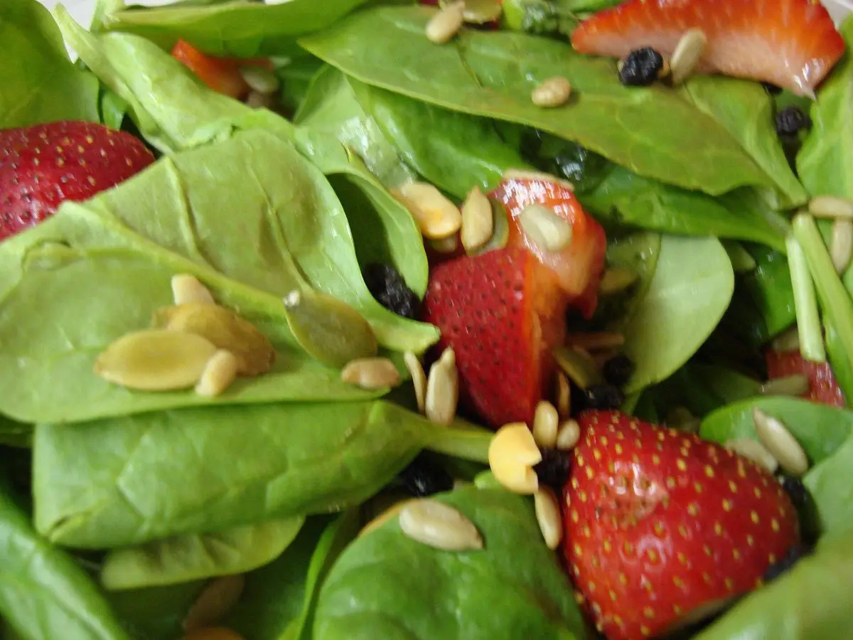 Ensalada de hojas de espinaca con fresas frescas y semillas de calabaza o girasol