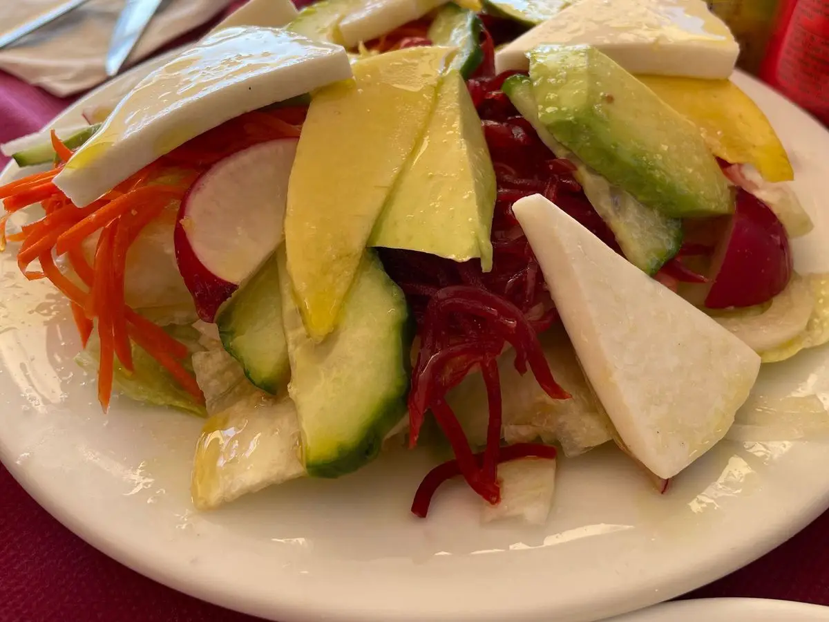 Ensalada con lonchas de queso de cabra, aguacate, remolacha rallada, rabanito, pepino y zanahoria