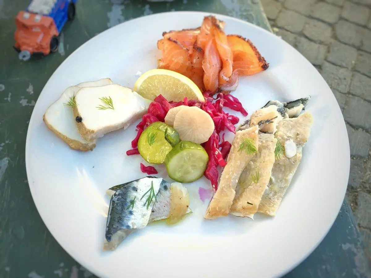 Plato blanco con pescados ahumados, pepino, remolacha y pan