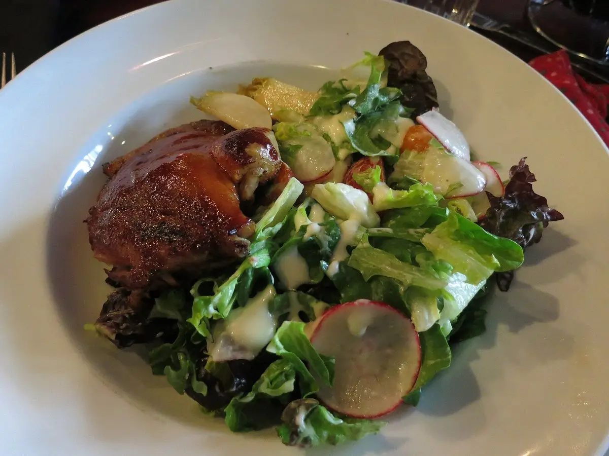 Plato con muslo de pato confitado y ensalada de hojas, rábano y endibia
