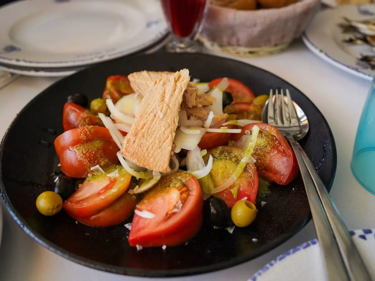 Ensalada de tomate, aceitunas y cebolla con atún en un plato negro