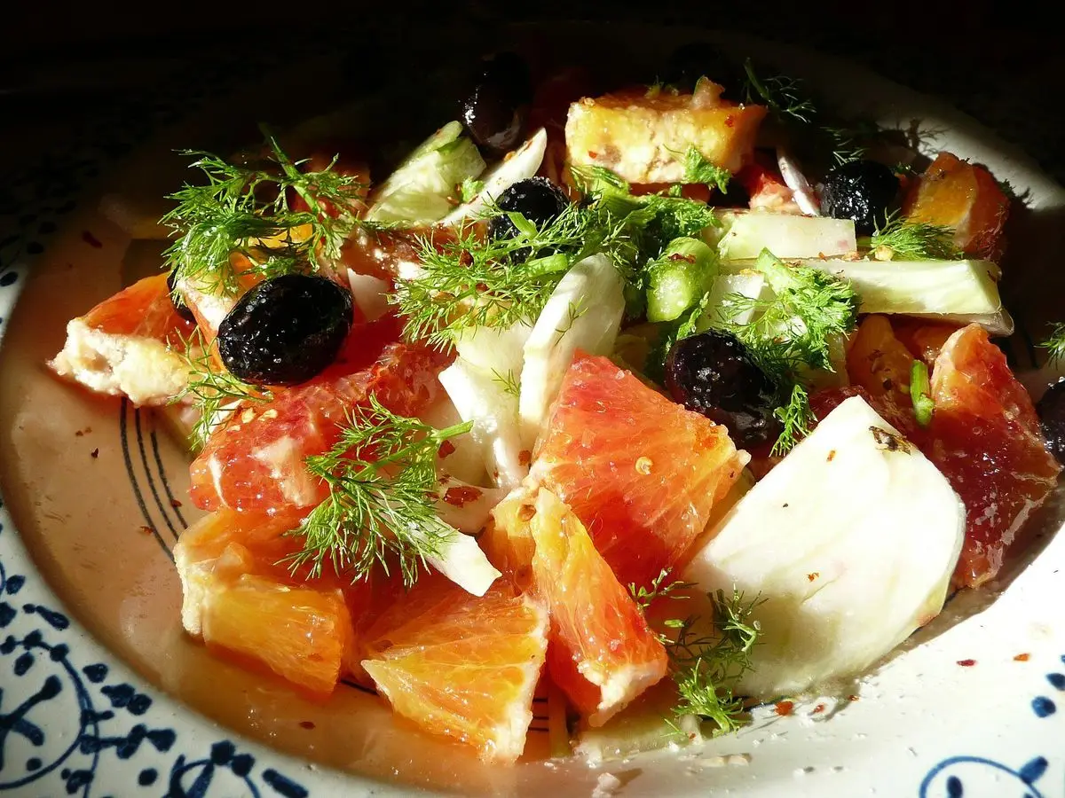 Ensalada de naranja, aceitunas negras, hinojo y eneldo en un plato de cerámica decorado