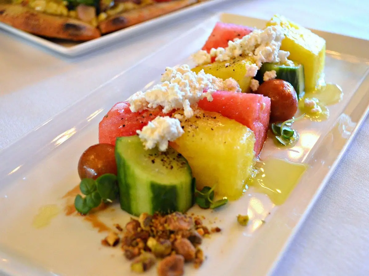 Fuente con dados de sandía, pepino, queso feta desmenuzado y frutos secos
